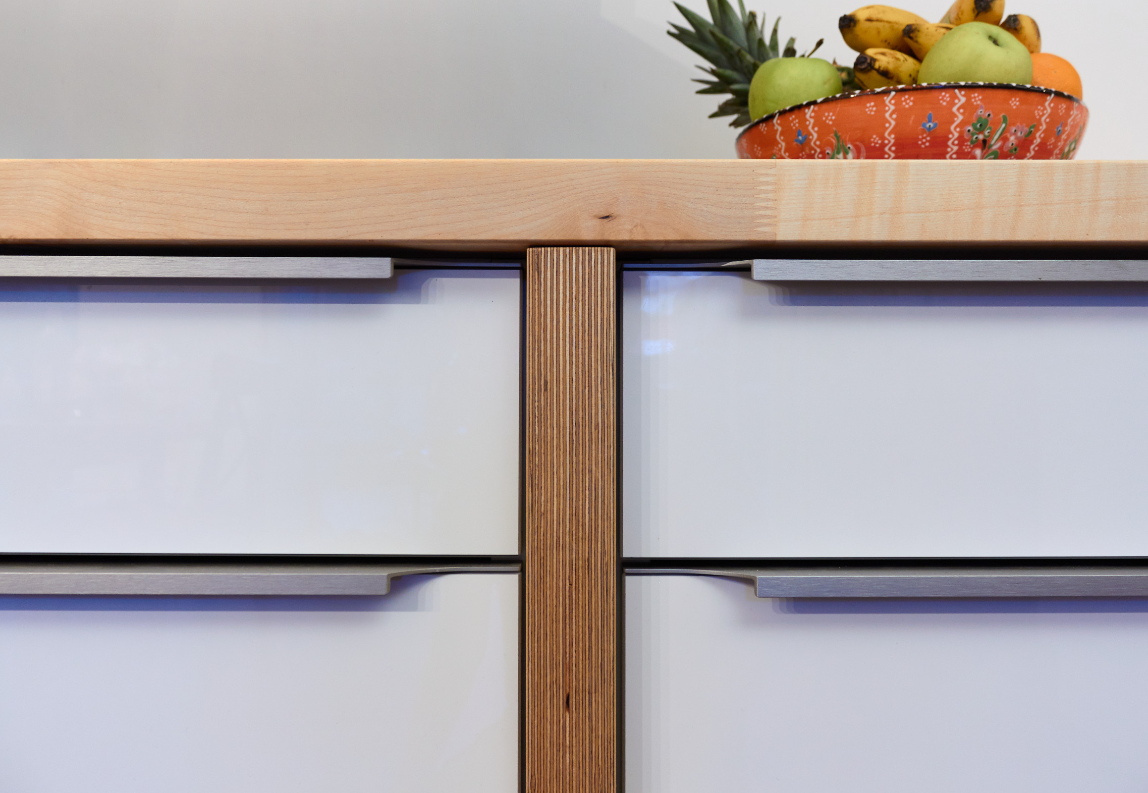 Küche mit weißen Hochglanzfronten, Massivholzarbeitsplatte Ahorn, Multiplex-Stollen