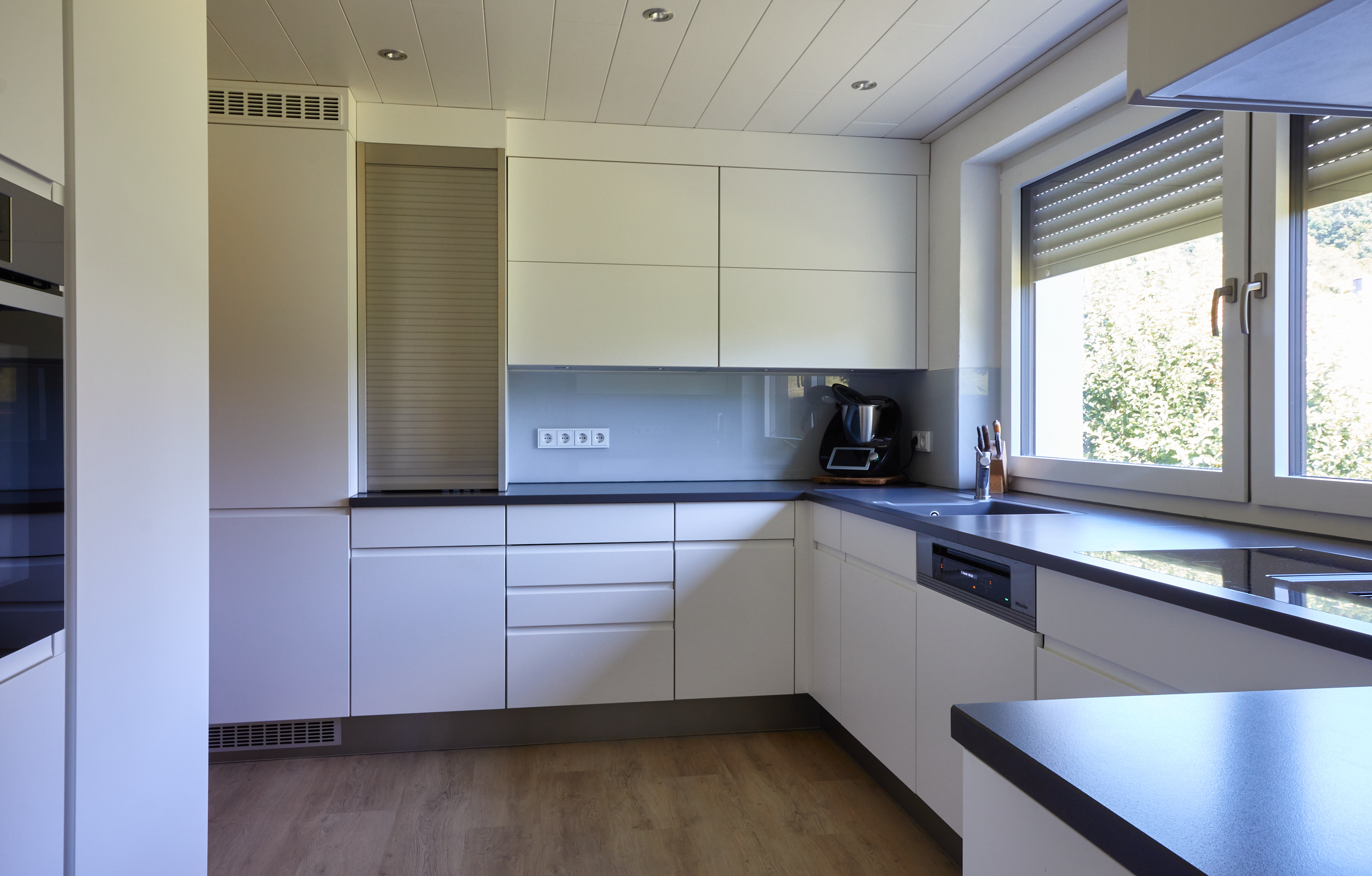 Küche Wolter Lackfronten mit Grifffräsungen, AKP Quarzsteinarbeitsplatte und Glasrückwand