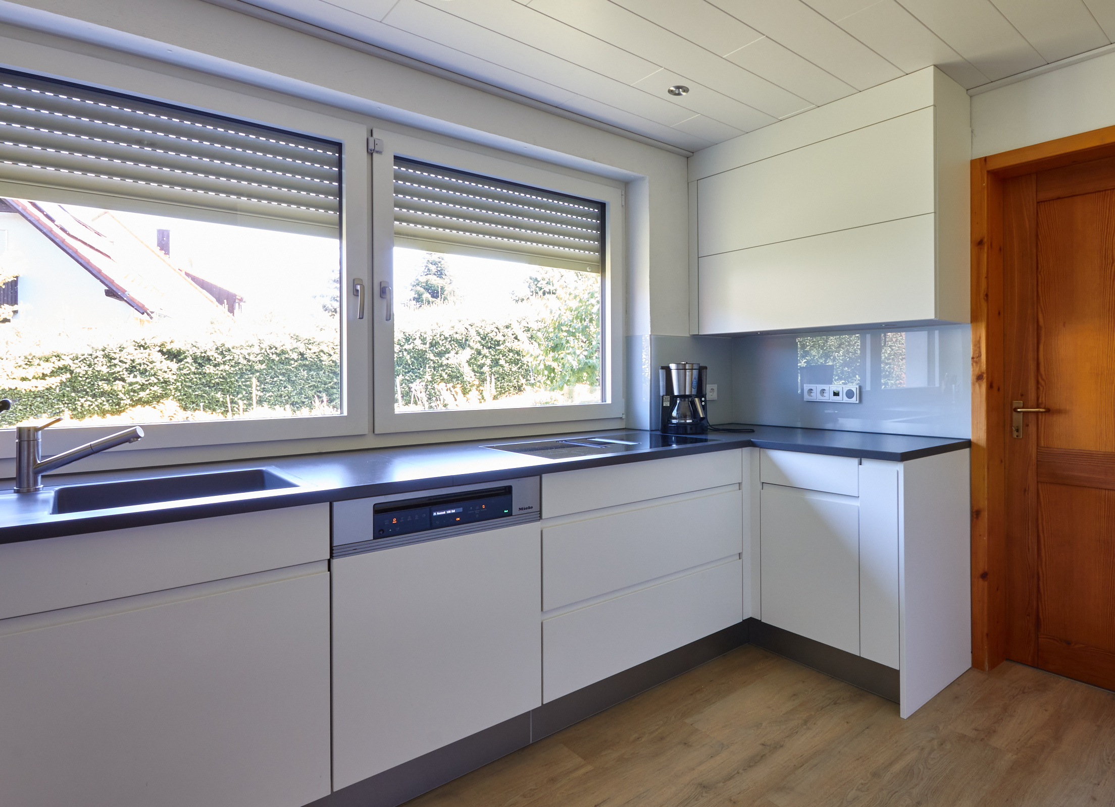 Küche Wolter Lackfronten mit Grifffräsungen, AKP Quarzsteinarbeitsplatte und Glasrückwand